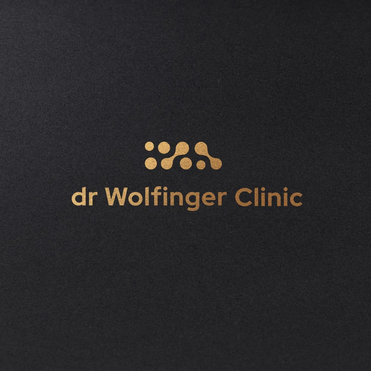 Logo dr Wolfinger Clinic w złocie na czerni